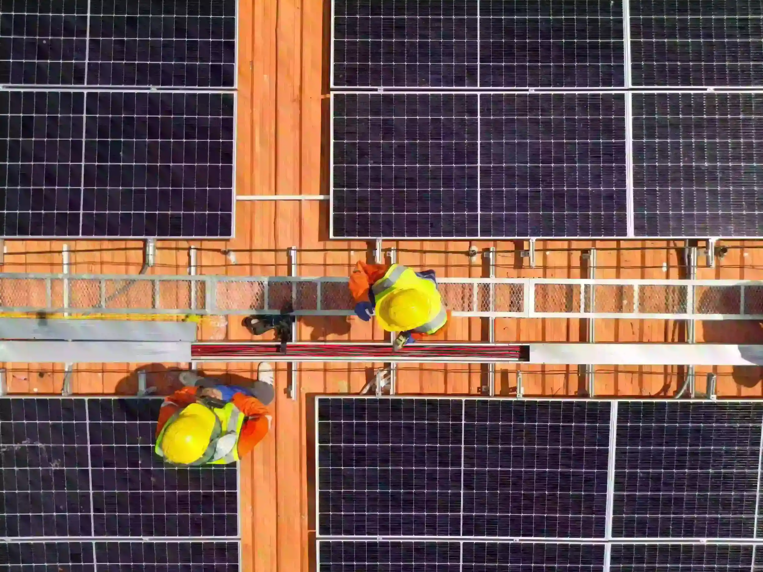 Two solar technicians working on rooftop panels viewed from above, showcasing National Solar Network’s hands-on local expertise.