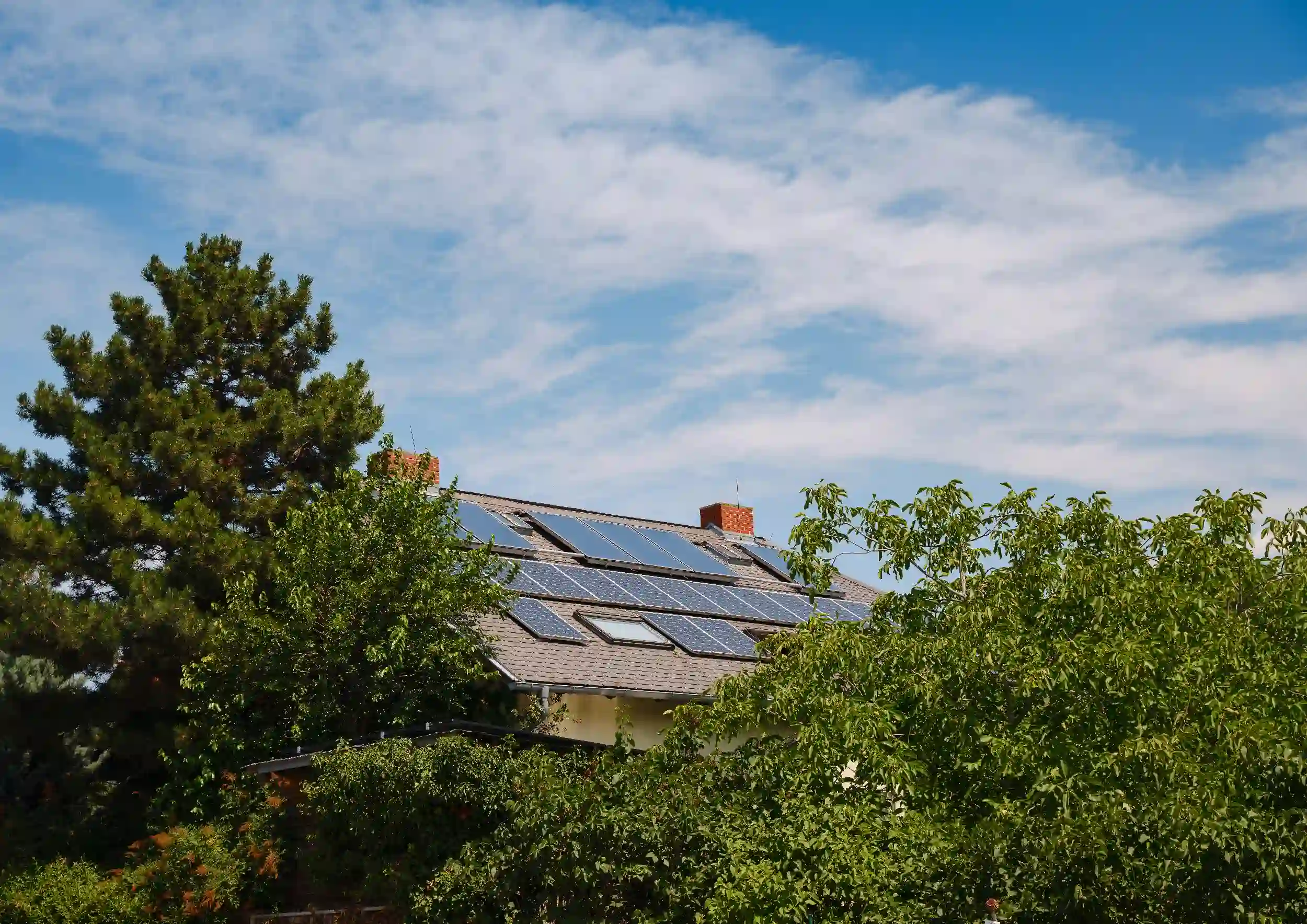 Residential solar panel system installed on a home in Gracemere, partially surrounded by trees and greenery.
